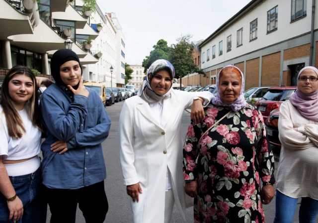 Fünf Muslimas stehen nebeneinander auf einer Straße.